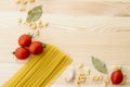 Cooking food background with free space for text. Composition with pasta, tomato, eggs, garlic, bay leaf over the wood background