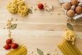 Cooking food background with free space for text. Composition with pasta, tomato, eggs, garlic, bay leaf over the wood background