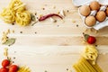 Cooking food background with free space for text. Composition with pasta, tomato, eggs, garlic, bay leaf over the wood background