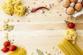 Cooking food background with free space for text. Composition with pasta, tomato, eggs, garlic, bay leaf over the wood background