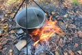 Cooking food on a campfire in the woods. Close-up of camp pot hanging over the fire in the autumn forest.