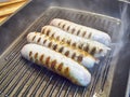 Cooking four sausages on a grill.