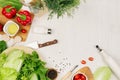 Cooking fresh raw spring salad of green and red vegetables, spices, oil with wooden kitchenware on white wooden background, border Royalty Free Stock Photo