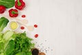 Cooking fresh spring salad of green and red vegetables, spices on white wooden background, border, top view. Royalty Free Stock Photo