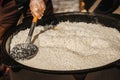 Cooking of freshly pilaf in large metal cauldron, cook mixes rice with scoop