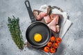 Cooking fried Egg in a skillet with bacon and tomato. Gray background. Top view Royalty Free Stock Photo