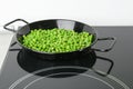 Cooking frozen peas on induction stove. Vegetable preservation