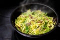 Cooking green savoy cabbage with red onions in a black pan on a stove, healthy winter vegetable Royalty Free Stock Photo