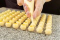 Cooking handmade chocolates. A confectioner pours liquid white chocolate into molds. Close-up. Selective focus. Royalty Free Stock Photo