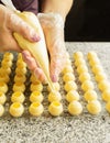 Cooking handmade chocolates. A confectioner pours liquid white chocolate into molds. Close-up. Selective focus. Royalty Free Stock Photo