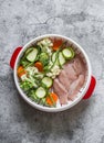 Cooking healthy food concept. Fresh vegetables broccoli, zucchini, carrots, asparagus and chicken fillet in a steamer on a gray