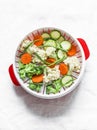 Cooking healthy food concept. Fresh vegetables broccoli, zucchini, carrots, asparagus in a steamer on a light background, top view