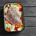 Cooking healthy food - raw ingredients: potatoes, zucchini, carrots, onions, garlic, peppers and fish sea bass in a baking dish Royalty Free Stock Photo