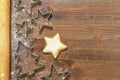 Cookie in the form of star, cookie cutters and dough gurney on wooden background