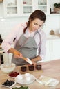 Young woman pastry chef fills muffins with dough.