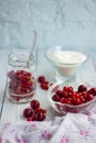 Red berries in a glass transparent bowl and sugar; currants in a jar on a light background Royalty Free Stock Photo