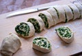 Cooking homemade buns with green onions, nettles, cheese and egg, the second step. Folding the roll with the filling and cutting