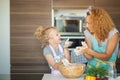 Mother and child daughter girl having fun while making dinner at the kitchen. Royalty Free Stock Photo