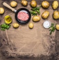 Cooking homemade hamburger with fried potatoes, fresh ground beef in a small frying pan herbs, oil and spices on wooden rusti Royalty Free Stock Photo