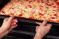 Cooking homemade pizza in the oven. A young woman puts uncooked pizza in the oven on a baking pan. Appetizing pizza with delicious Royalty Free Stock Photo