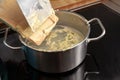 Cooking homemade spaetzle, egg pasta dough is scrapped from a wooden board into a pot with boiling water, typical dish in Schwaben Royalty Free Stock Photo