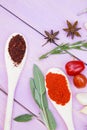 Cooking Hot Spicy Food Concept. Dry spices,beans and herbs in plastic cup, glass jar with cork and wooden spoon, purple wooden bac Royalty Free Stock Photo