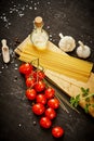 Tomatoes garlic salt olive peppers and pasta on a black table Royalty Free Stock Photo