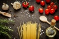 Tomatoes garlic salt olive peppers and pasta on a black table Royalty Free Stock Photo