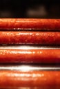 Close-up of grilled sausages in a cafe, which are fried to a brown crust. Cooking ingredients for a hot dog. Vertical photo