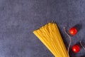 Bunch of raw Italian pasta with cherry tomatoes isolated on stone grey background. Royalty Free Stock Photo