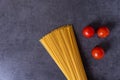 Bunch of raw Italian pasta with cherry tomatoes isolated on stone grey background. Royalty Free Stock Photo