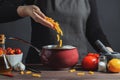 Cooking italian pasta in a pot in the kitchen, Chef preparing food, meal. The woman-the cook throws into the pot the pasta fusilli