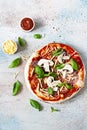 Cooking Italian pizza with tomato sauce, fresh tomatoes, cheese, mushrooms, salami slices and basil . Royalty Free Stock Photo