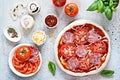 Cooking Italian pizza with tomato sauce, fresh tomatoes, cheese, mushrooms, salami slices and basil . Royalty Free Stock Photo