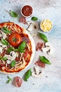 Cooking Italian pizza with tomato sauce, fresh tomatoes, cheese, mushrooms, salami slices and basil . Royalty Free Stock Photo