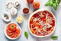 Cooking Italian pizza with tomato sauce, fresh tomatoes, cheese, mushrooms, salami slices and basil . Royalty Free Stock Photo