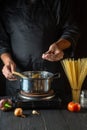 Cooking Italian spaghetti in the restaurant kitchen. The chef adds salt to Stock pot of boiling water. Vertical image Royalty Free Stock Photo