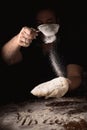 Cooking, kneading dough. Male hands sift flour onto the dough on a dark background