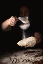Cooking, kneading dough. Male hands sift flour onto the dough on a dark background