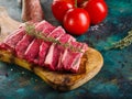 Cooking meat dishes. Raw steaks on a wooden cutting board, tomatoes and spices, seasonings in glass jars. Restaurant, hotel, cafe Royalty Free Stock Photo