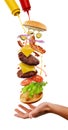 Cooking of mega burger. Flying multilayer dish with splashes on white