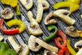 Cooking mushrooms with vegetables in hot seed oil in a frying grill pan with non-stick coating. Roasting colorful bell peppers