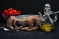 Cooking octopus in a pan with fresh raw ingredients: olive oil,