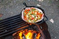 Cooking outdoors over campfire cast iron skillet bacon vegetables