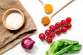 Cooking paella with vegetables and rice ingredients on white desk background top view