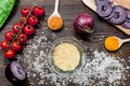 cooking paella with vegetables, spices and rice on wooden desk background top view