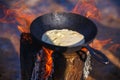 Cooking pancake in a pan on the fire of a Finnish candle