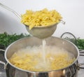 Cooking Pasta pour the penne pasta into a metal pot of boiling water. Boiled penne on a steel colander, in a cooking class Royalty Free Stock Photo