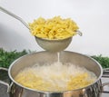 Cooking Pasta pour the penne pasta into a metal pot of boiling water. Boiled penne on a steel colander, in a cooking class Royalty Free Stock Photo