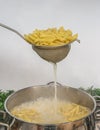 Cooking Pasta pour the penne pasta into a metal pot of boiling water. Boiled penne on a steel colander, in a cooking class Royalty Free Stock Photo